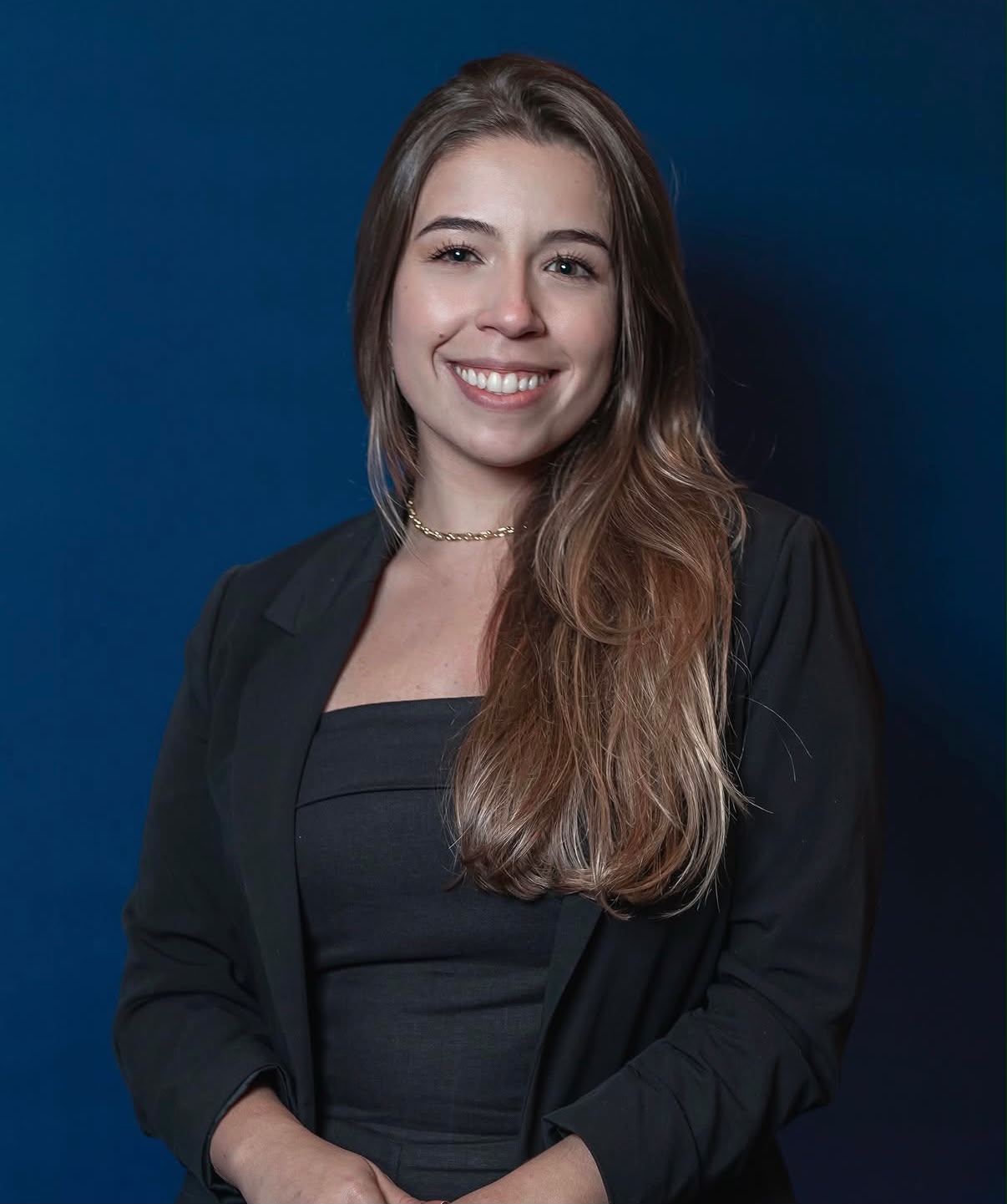 Vitória Maldonado Ourique, advogada tributarista, em retrato profissional sobre fundo azul-marinho.